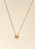 Gold heart-shaped pendant necklace on a beige background