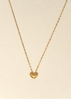 Gold heart-shaped pendant necklace on a beige background