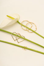 Gold heart-shaped and circular gold hoops on a white flower in the background.