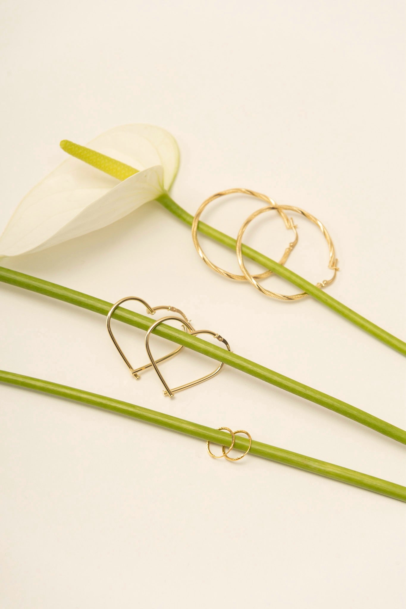 Gold heart-shaped and circular gold hoops on a white flower in the background.