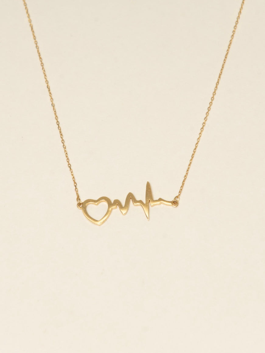 Gold necklace with heart and line design on a beige background
