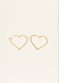 Gold heart-shaped hoop earrings on a light beige background